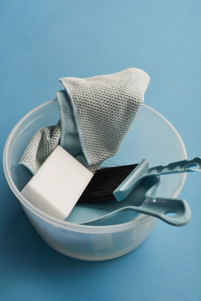 Cleaning set in a plastic container of a blue dustpan and brush melamine sponge and microfiber on a blue surface